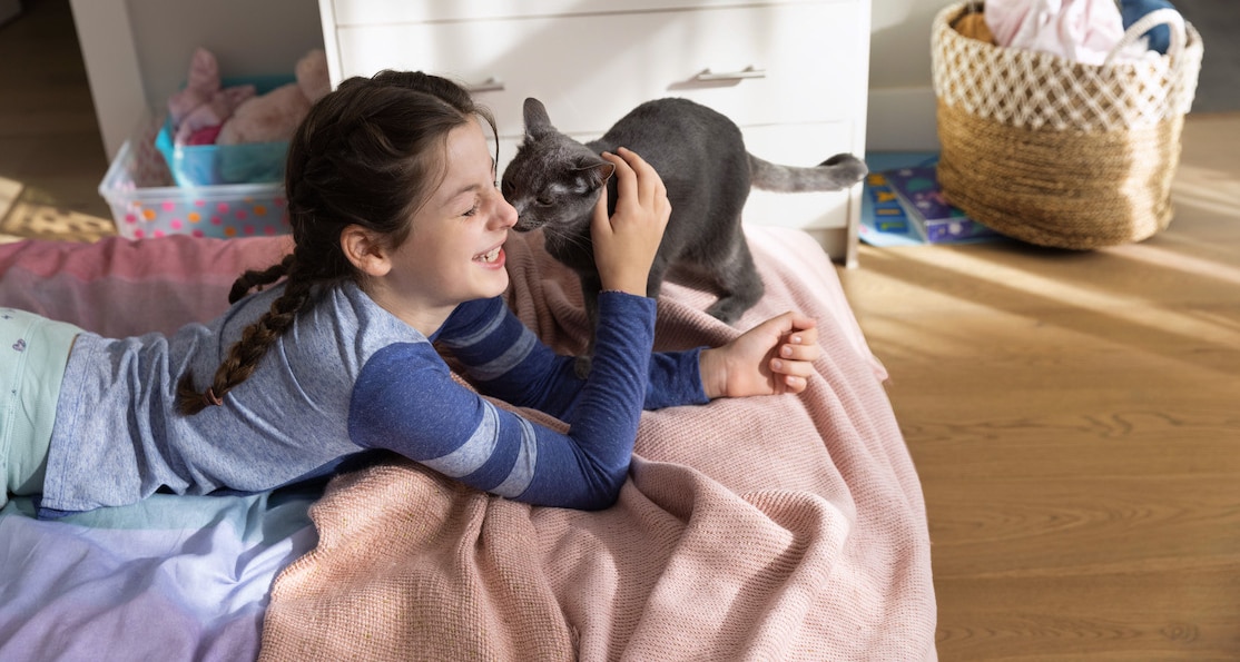 Black cat licking smiling girl on face